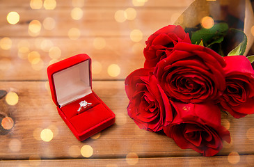 Image showing close up of diamond engagement ring and red roses