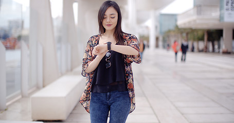 Image showing Young woman checking her wristwatch