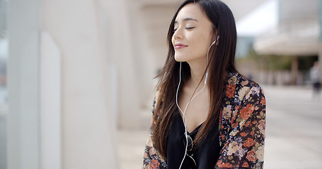 Image showing Trendy young woman listening to music in town