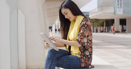 Image showing Young woman sitting reading her tablet