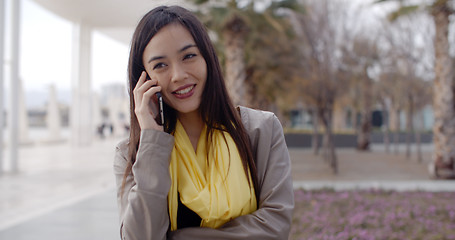 Image showing Young woman standing talking on her mobile phone
