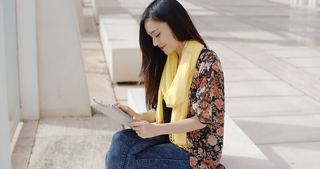 Image showing Young woman sitting reading her tablet