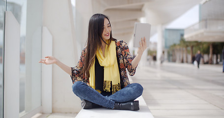 Image showing Smiling woman waving at her tablet computer