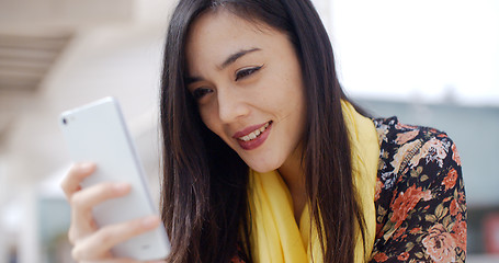 Image showing Young woman reading a message on mobile