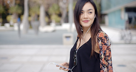 Image showing Young woman walking listening to music