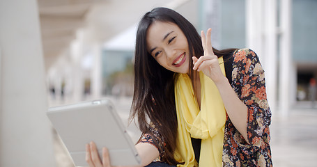 Image showing Cheerful female gesturing for tablet camera