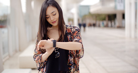 Image showing Young woman checking her wristwatch