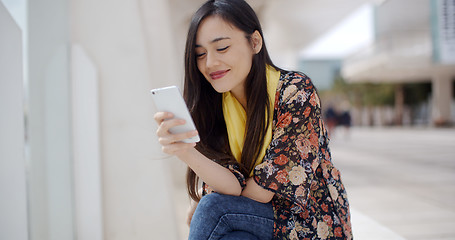 Image showing Chic young woman reading a mobile message