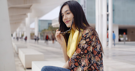 Image showing Thoughtful young woman sitting on a promenade