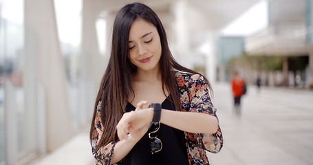 Image showing Young woman looking at the time with a smile