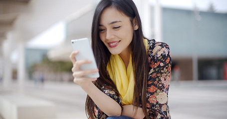 Image showing Chic young woman reading a mobile message
