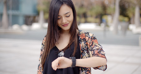 Image showing Young woman looking at the time with a smile