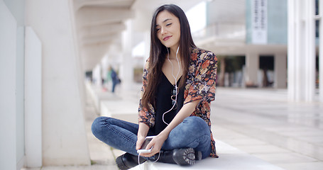 Image showing Trendy young woman listening to music in town