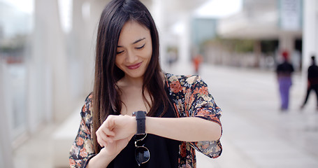 Image showing Young woman looking at the time with a smile