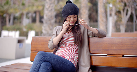 Image showing Trendy young woman relaxing on a park bench