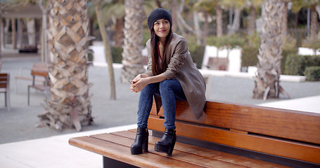 Image showing Fashionable young woman sitting waiting on a bench