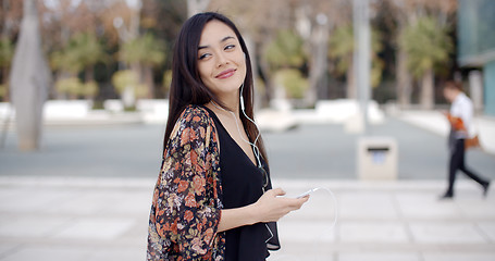 Image showing Young woman walking listening to music