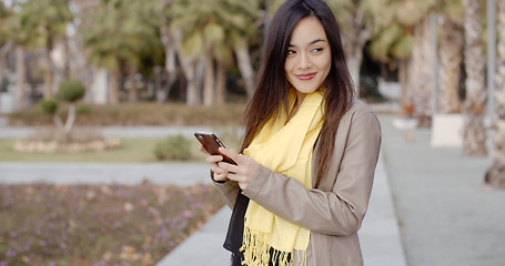 Image showing Happy young woman sending a text message