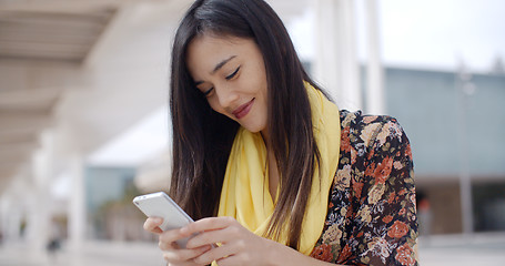 Image showing Chic young woman checking her text messages