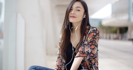 Image showing Trendy young woman listening to music in town