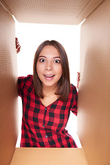 Image showing Girl opening a carton box and looking inside