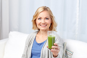 Image showing happy woman drinking green juice or shake at home