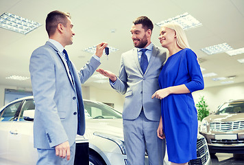 Image showing happy couple with car dealer in auto show or salon