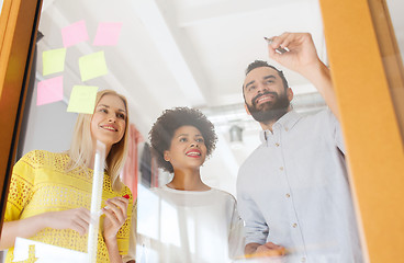 Image showing happy creative team writing on stickers at office