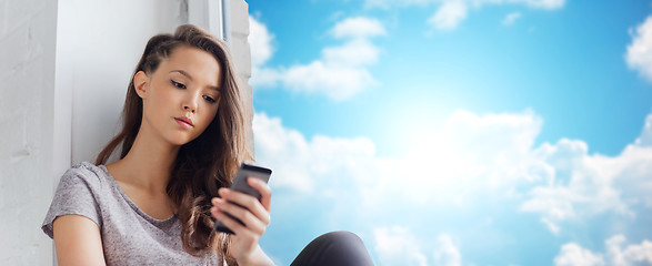 Image showing sad pretty teenage girl with smartphone texting