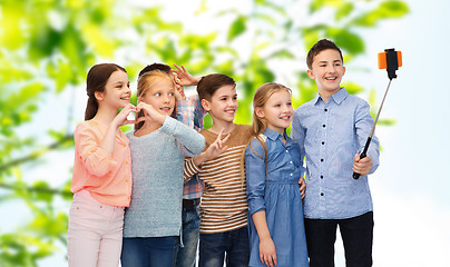 Image showing happy children with smartphone and selfie stick