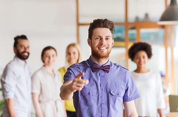 Image showing happy man pointing finger at you over office team