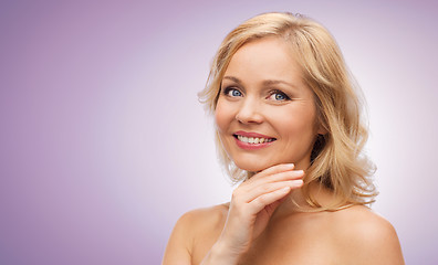 Image showing smiling woman with bare shoulders touching face