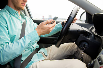 Image showing close up of man with smartphone driving car