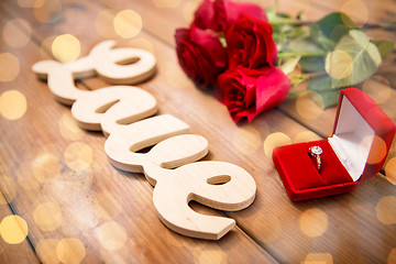 Image showing close up of diamond ring, red roses and word love