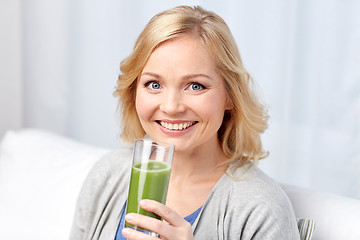 Image showing happy woman drinking green juice or shake at home