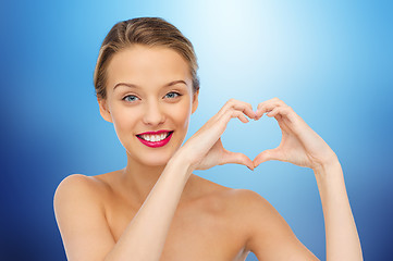 Image showing smiling young woman showing heart shape hand sign