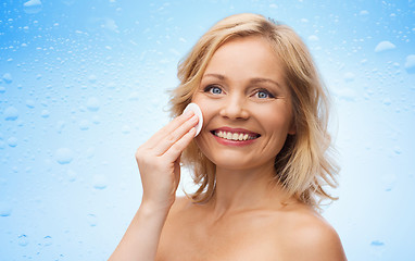 Image showing happy woman cleaning face with cotton pad