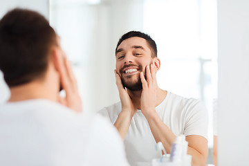 Image showing happy young man looking to mirror at home bathroom