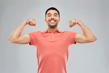 Image showing smiling man showing biceps over gray background