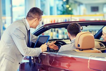 Image showing happy couple with car dealer in auto show or salon