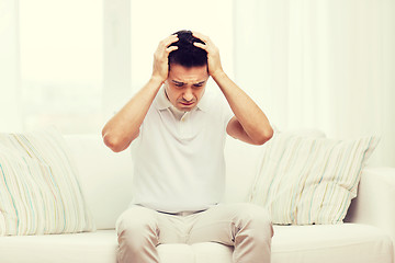 Image showing unhappy man suffering from head ache at home