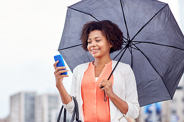 Image showing businesswoman with umbrella texting on smartphone