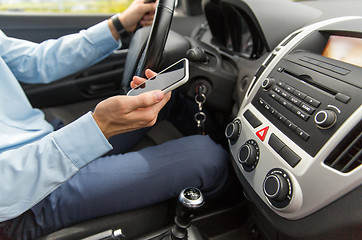 Image showing close up of man with smartphone driving car