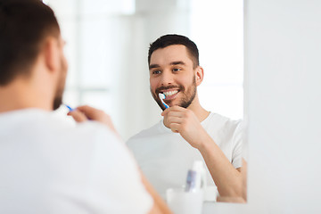 Image showing man with toothbrush cleaning teeth at bathroom