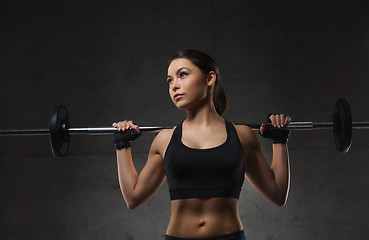 Image showing young woman flexing muscles with barbell in gym