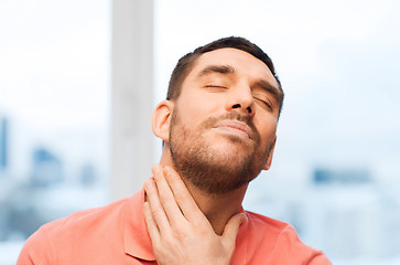 Image showing unhappy man suffering from throat pain at home