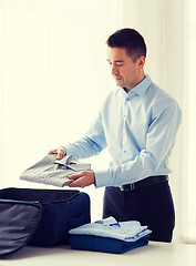 Image showing businessman packing clothes into travel bag