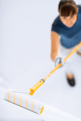 Image showing woman with roller and paint colouring the wall