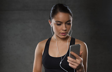 Image showing woman with smartphone and earphones in gym