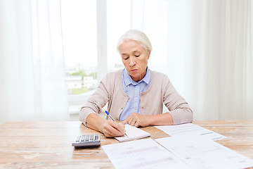 Image showing senior woman with papers and calculator at home